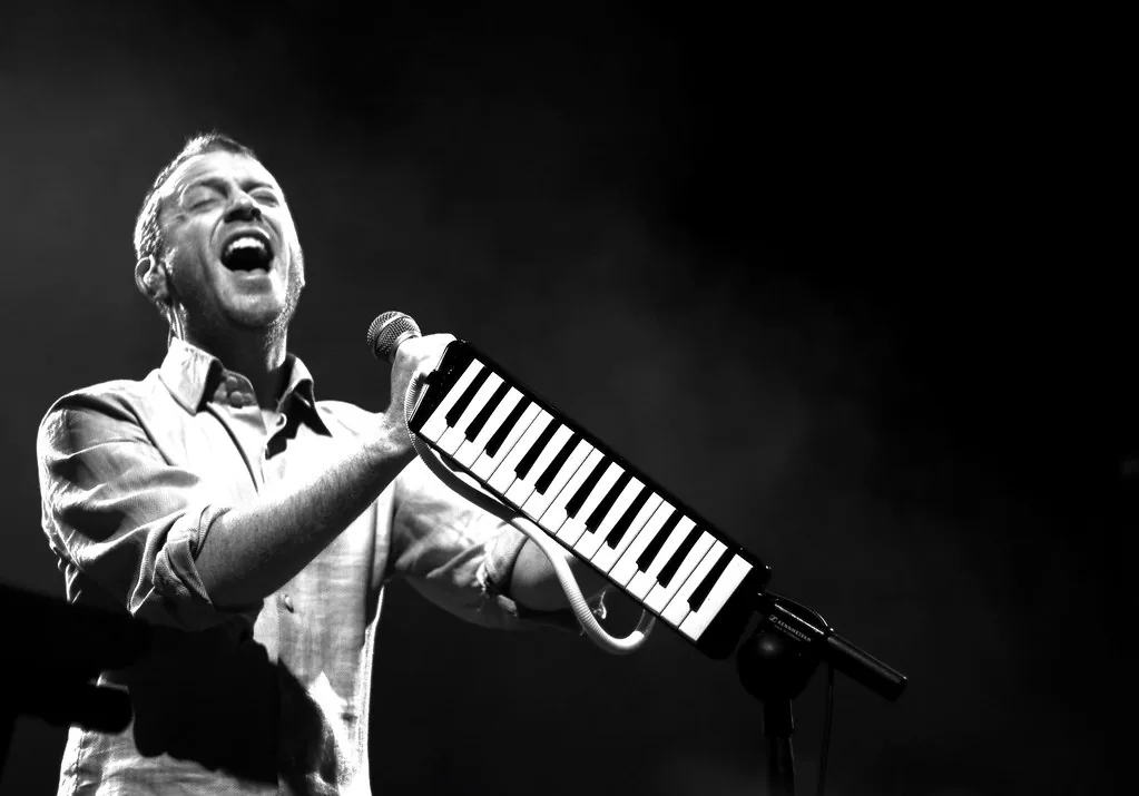 Singer playing a melodica on stage Singer playing a melodica on stage