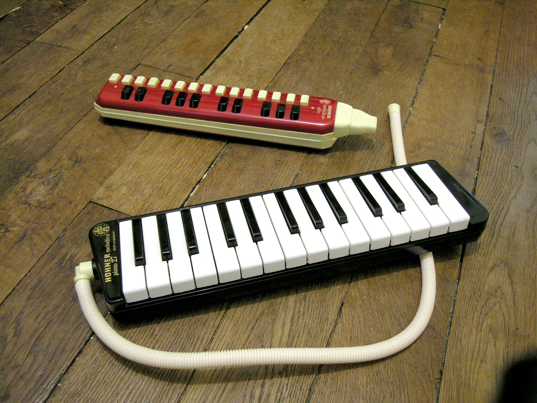 Two Hohner melodicas on a wooden floor Two Hohner melodicas on a wooden floor